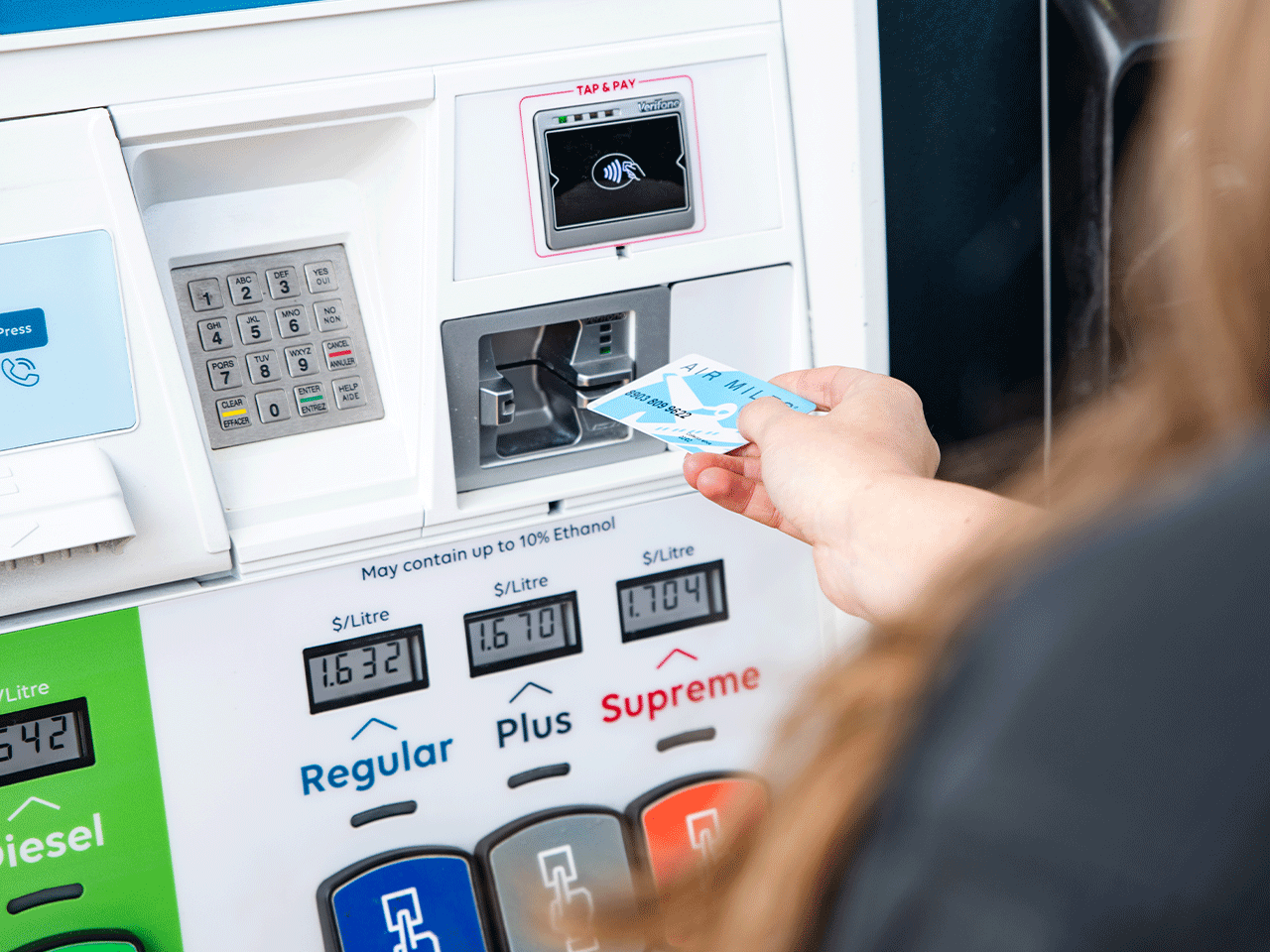 A person half visible in the frame, using an Air Mile card at the pump.