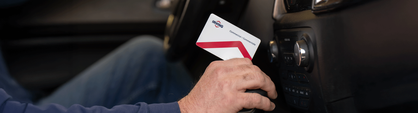 Irving Commercial Card held in a right hand which is placed on top of a throttle knob of a car, representing fuel solutions for businesses
